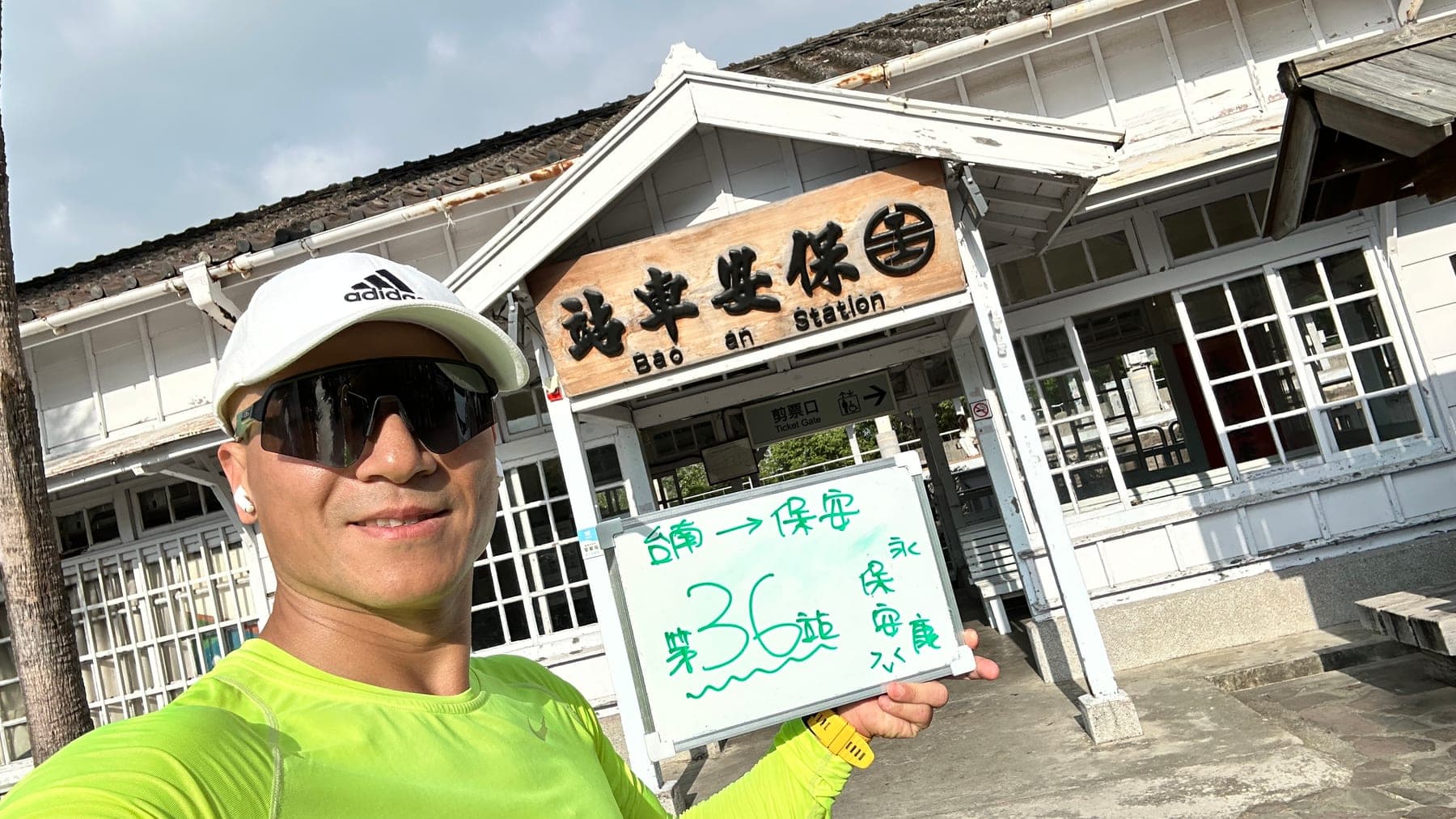 站主在保安站站牌前的走訪紀錄照,手持寫著「徒步環島 第 36 站 台南 → 保安」的白板
