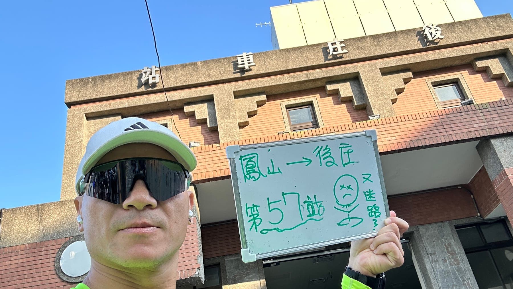 站主在後庄站站牌前的走訪紀錄照,手持寫著「徒步環島 第 57 站 鳳山 → 後庄」的白板