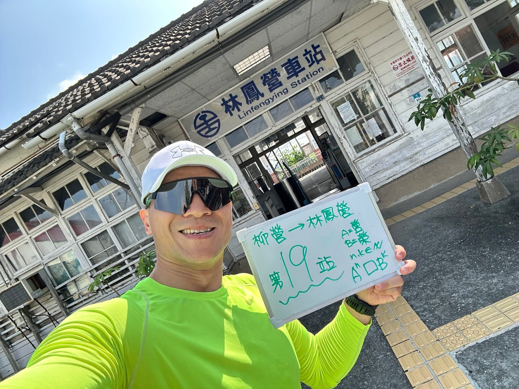 站主在林鳳營站站牌前的走訪紀錄照,手持寫著「徒步環島 第 19 站 柳營 → 林鳳營」的白板