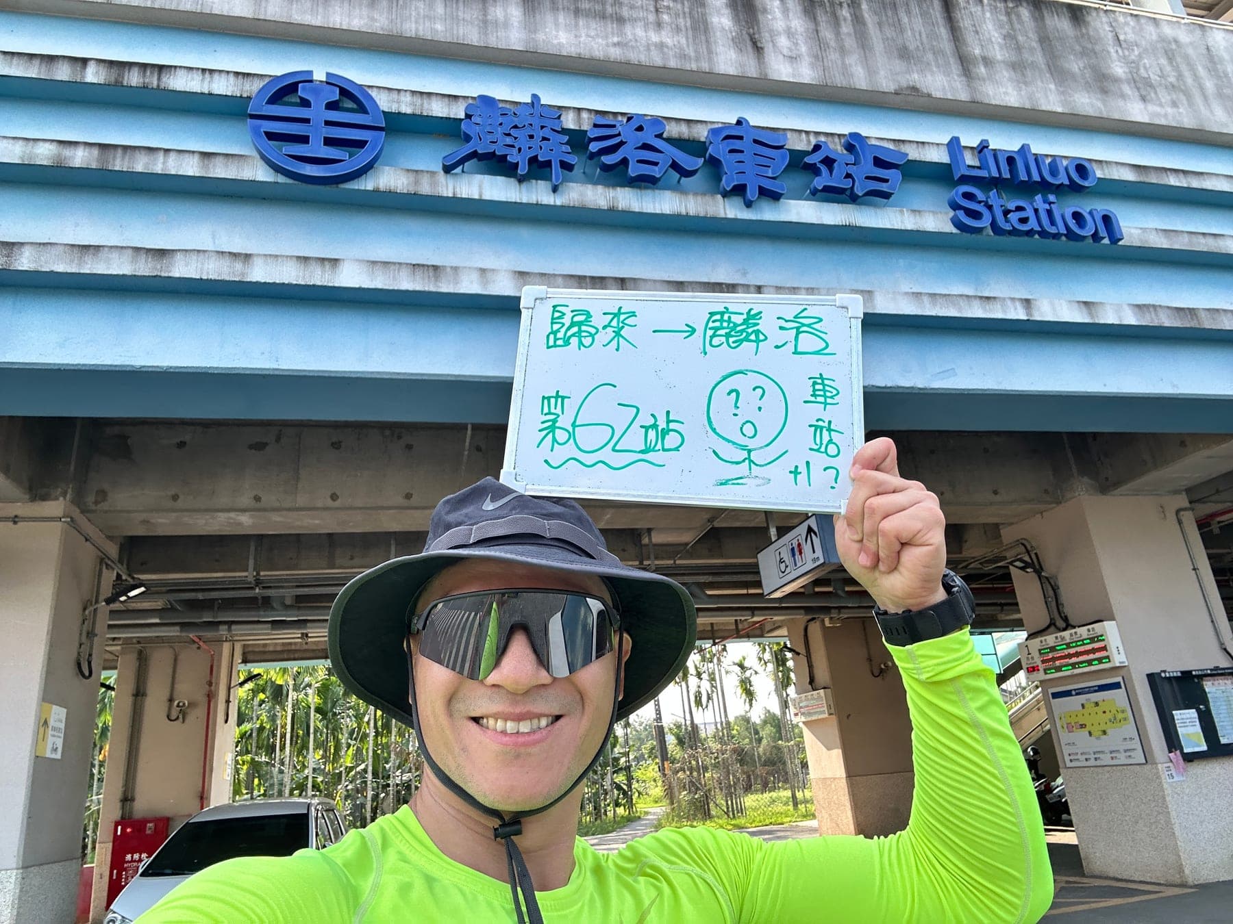 站主在麟洛站站牌前的走訪紀錄照,手持寫著「徒步環島 第 62 站 歸來 → 麟洛」的白板