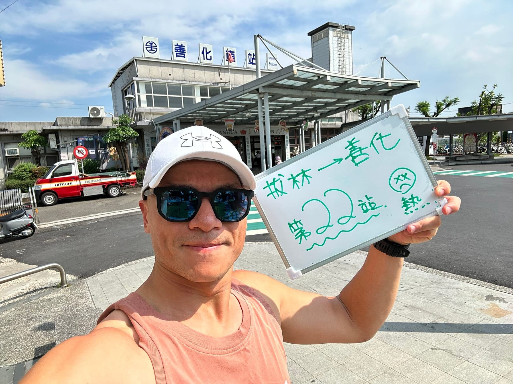 站主在善化站站牌前的走訪紀錄照,手持寫著「徒步環島 第 22 站 拔林 → 善化」的白板