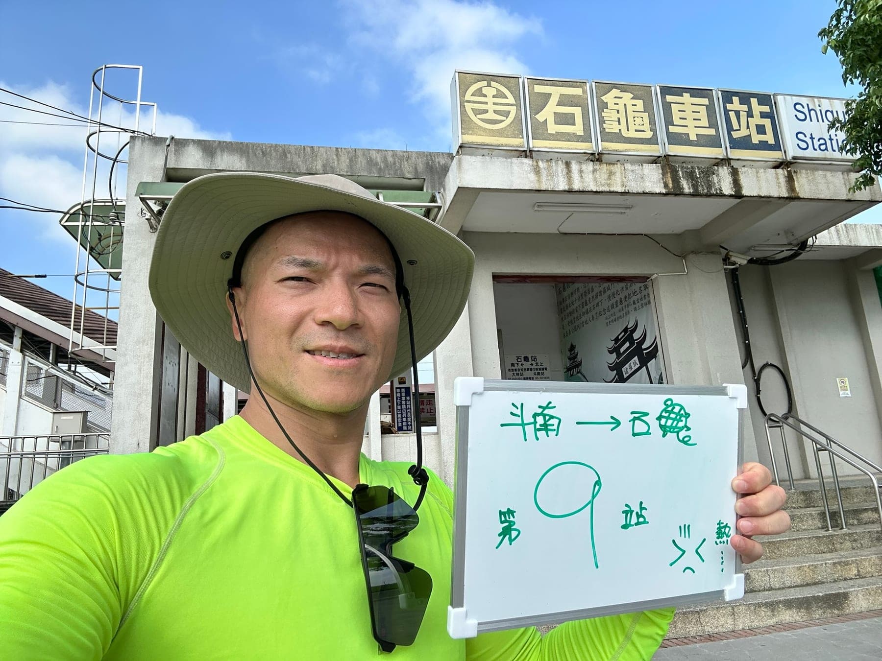 站主在石龜站站牌前的走訪紀錄照,手持寫著「徒步環島 第 9 站 斗南 → 石龜」的白板